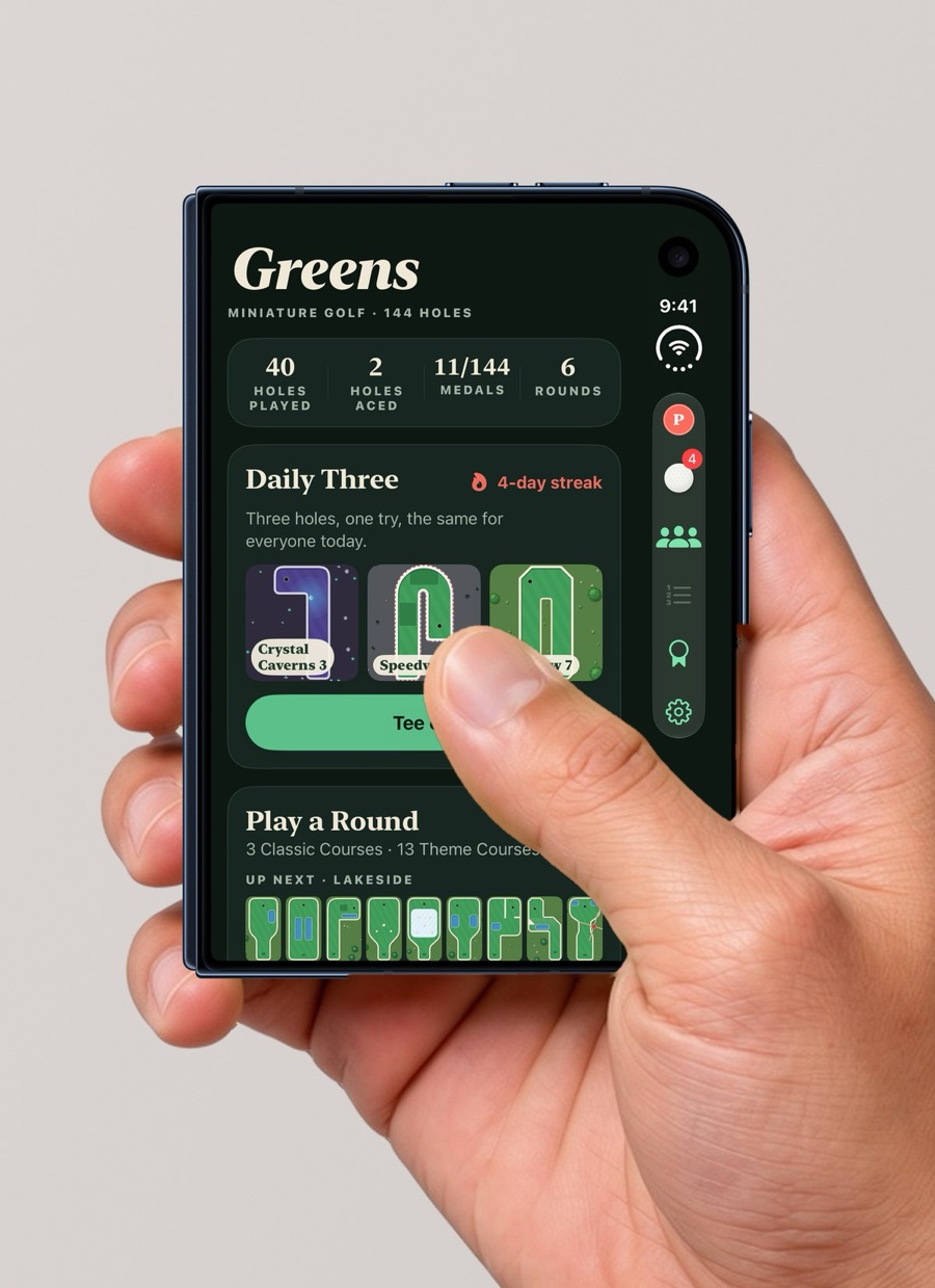 A hand holding iPhone Duo closed, with the Greens clubhouse on the outer screen and its buttons in the side bar on the right